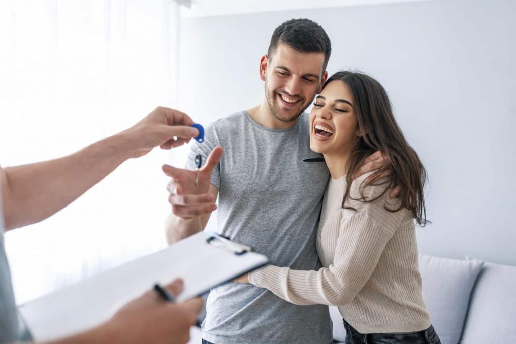 A happy couple getting the keys to their new home from a Blank & McCune buyer's agent